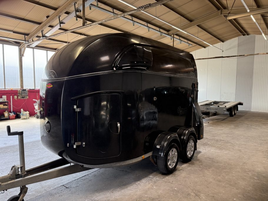 Schwarzer Anhänger mit runder Form, auf einem Trailer in einer geräumigen Halle.